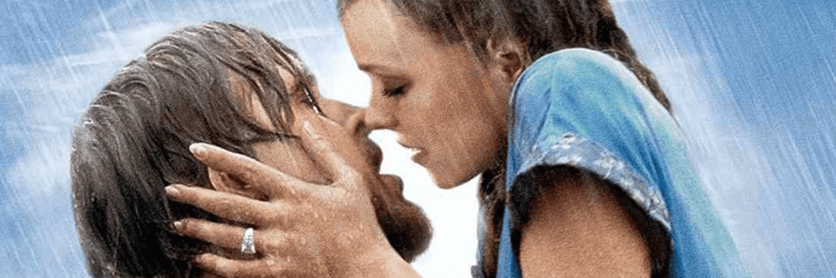 A couple kisses passionately in the rain, with blue sky in the background.
