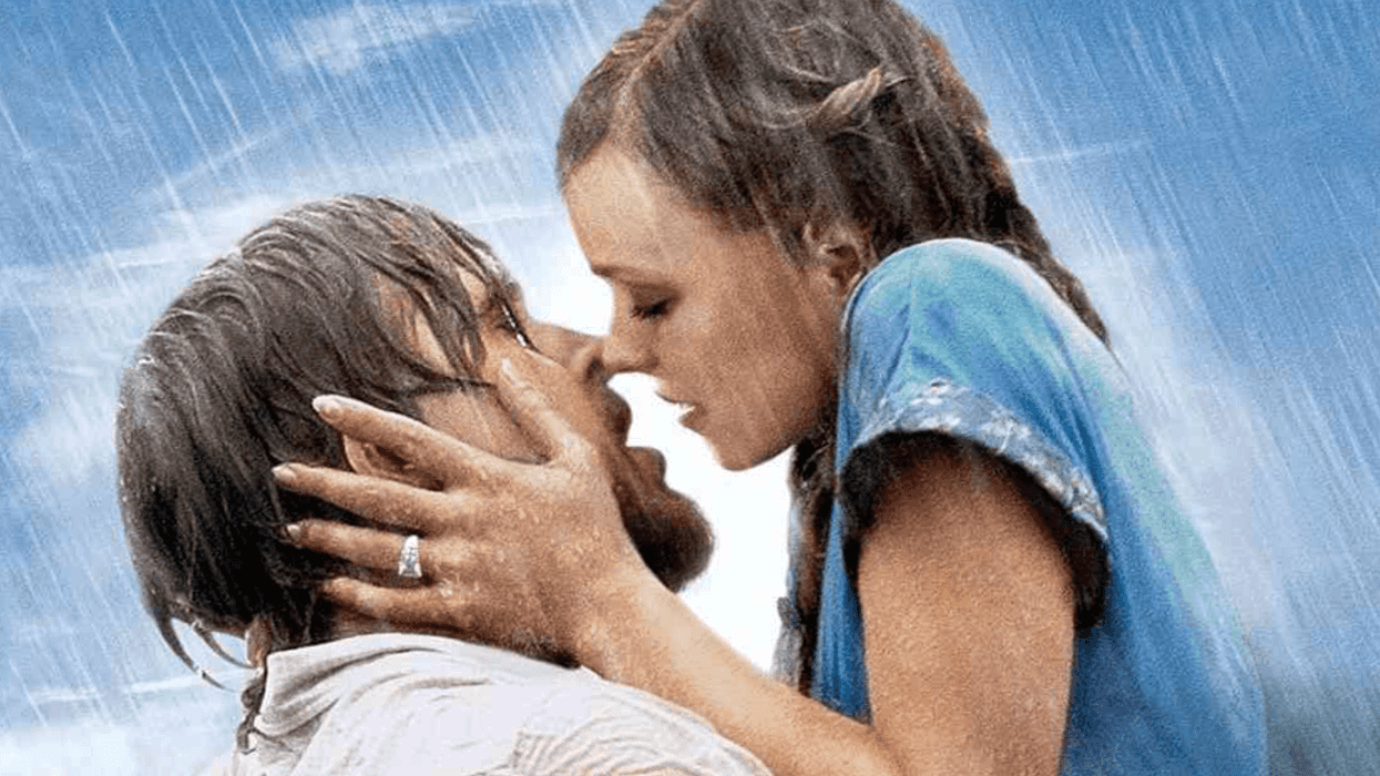 A couple kisses passionately in the rain, with blue sky in the background.