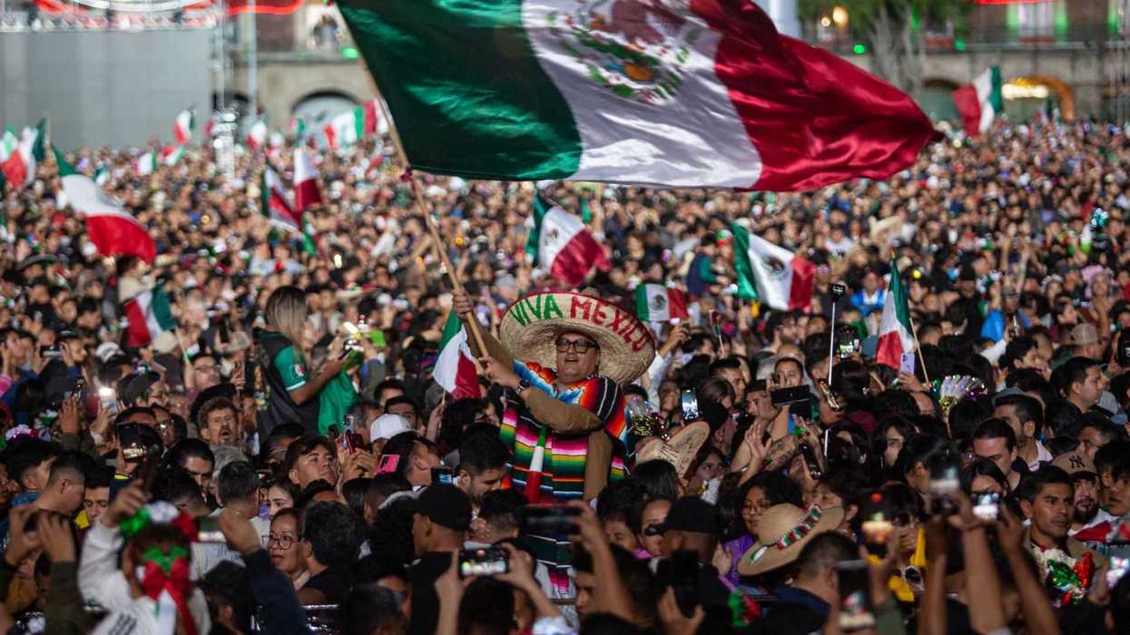 A crowded celebration with a Mexican flag and festive attire.