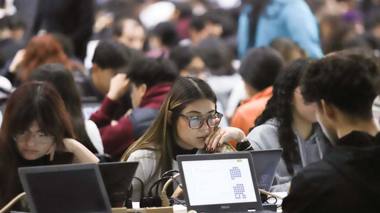 A group of people intensely working on laptops in a crowded room.