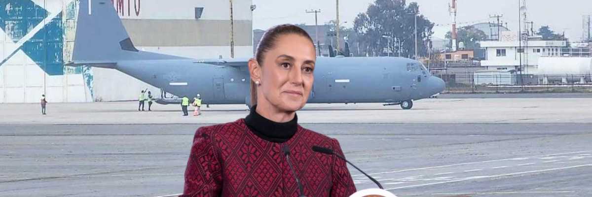 A person speaks at a podium near a military aircraft on an airfield.