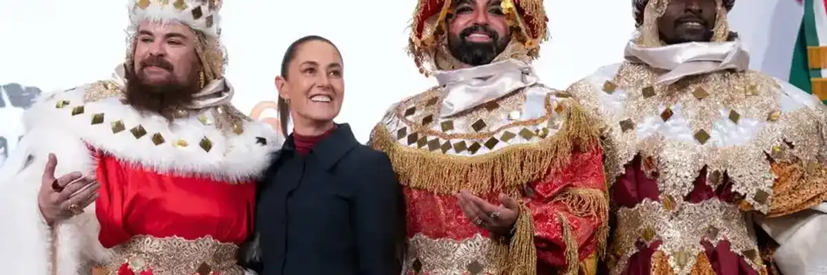 A person stands smiling with three individuals in ornate, colorful, kingly costumes.