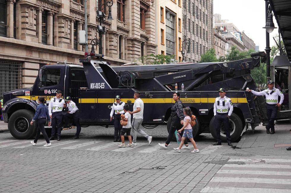 A tow truck parked on a city street with pedestrians and police officers nearby.
