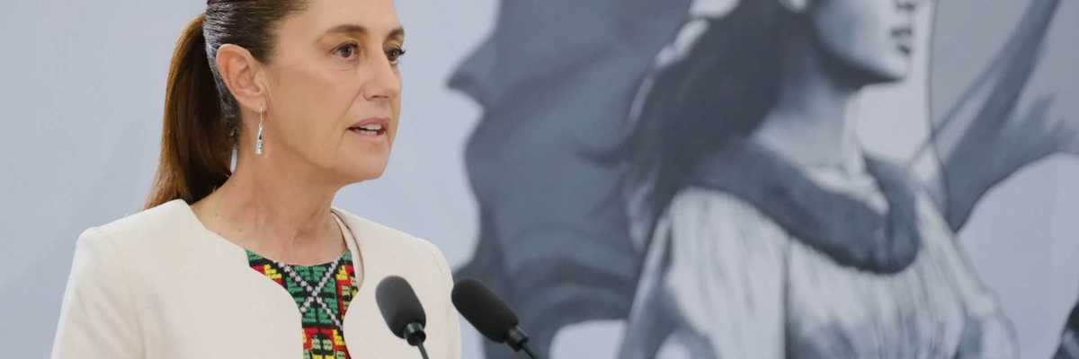 A woman speaks at a podium; a mural of a historical figure is in the background.
