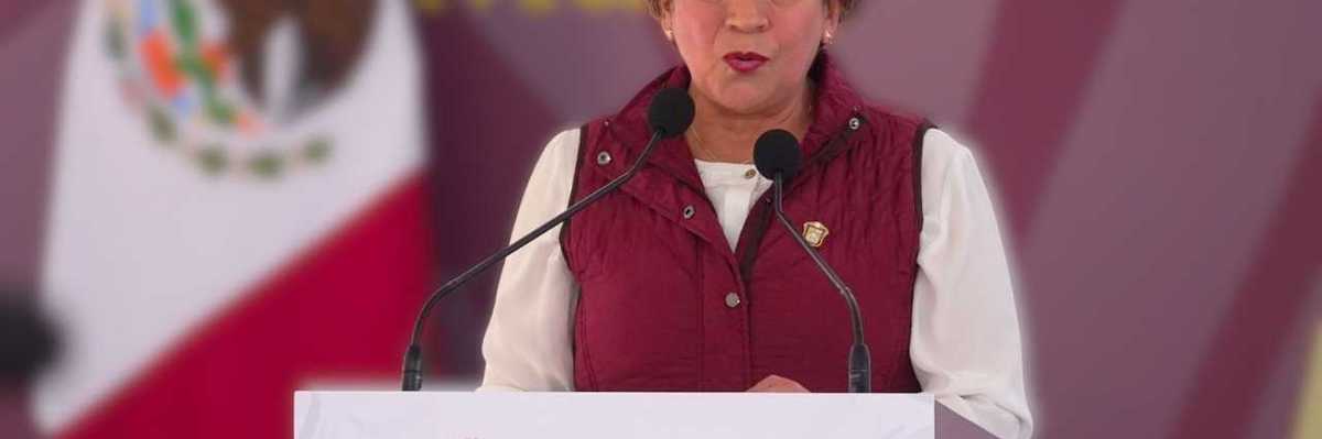 A woman speaks at a podium labeled "Gobierno de México" with a Mexican flag behind.