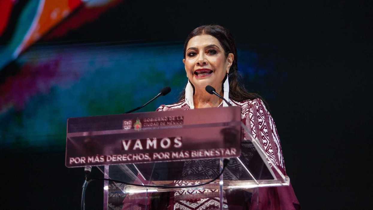 A woman speaks at a podium with a message about rights and well-being on it.