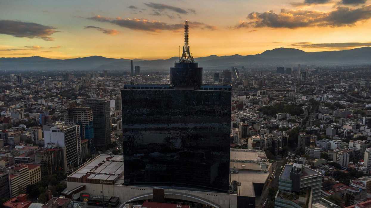 Aerial view of a cityscape at sunset with a tall, dark building in the foreground.