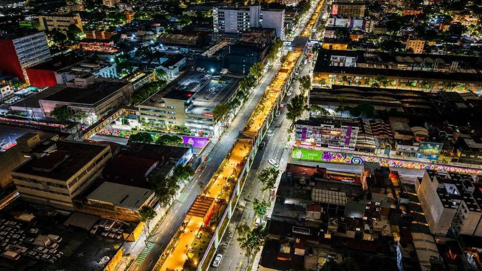 Aerial view of a vibrant cityscape at night with illuminated streets and colorful buildings.
