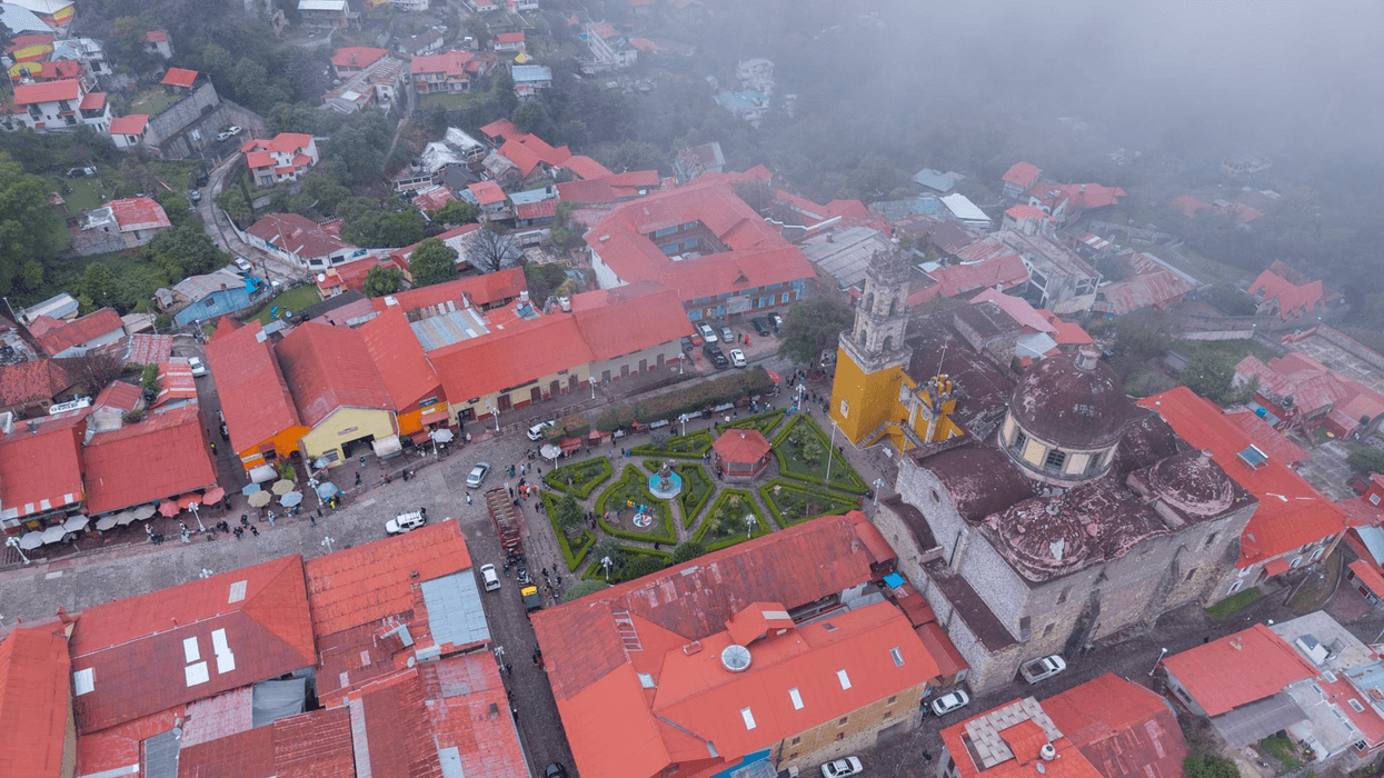Aerial view of a village with red-roofed buildings and a misty environment.