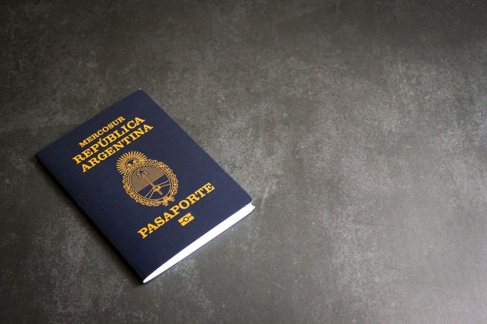 Argentinian passport on a dark surface, angled slightly left.