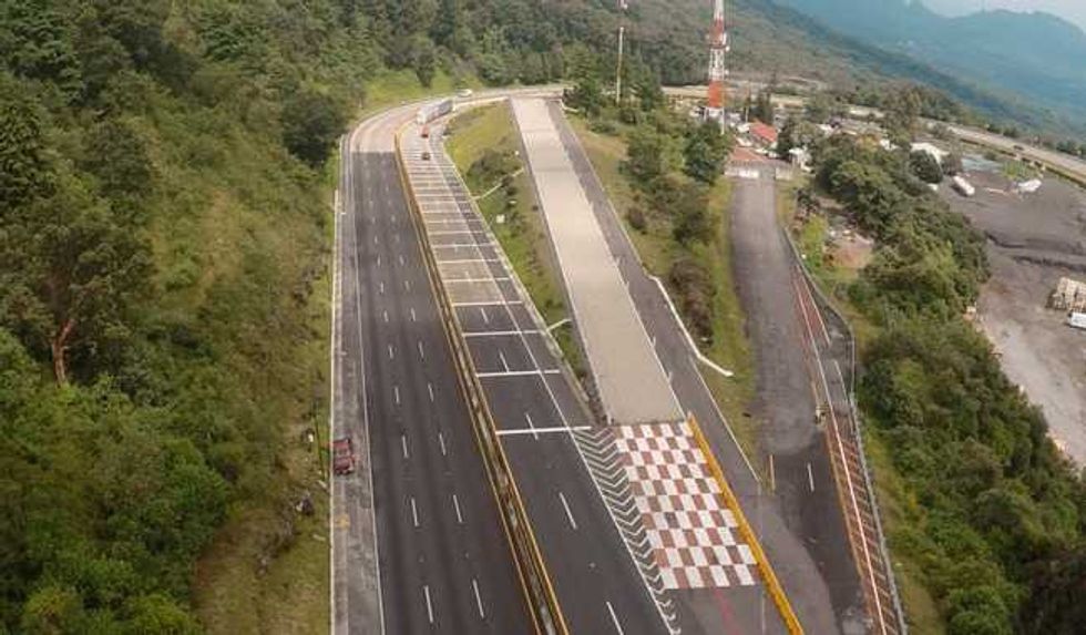 Arial view of a highway with an emergency truck ramp amidst lush green landscape.