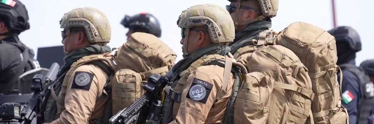 Armed soldiers in tactical gear and helmets stand together outdoors.