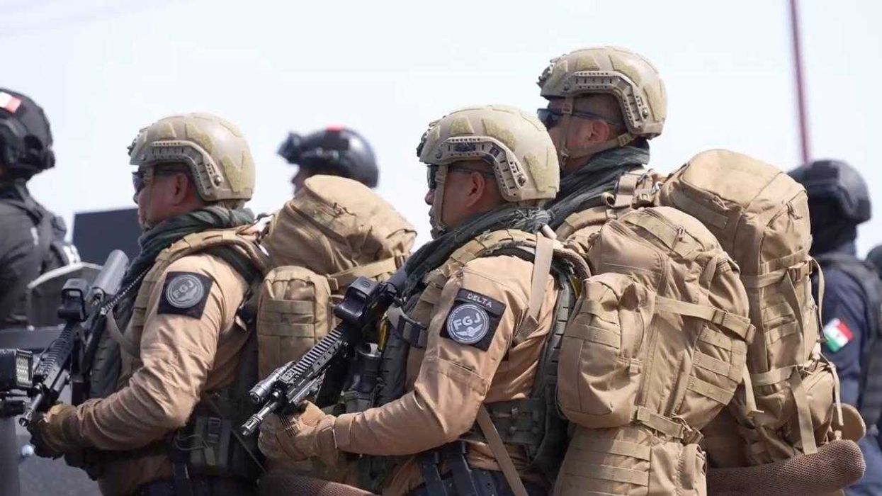 Armed soldiers in tactical gear and helmets stand together outdoors.
