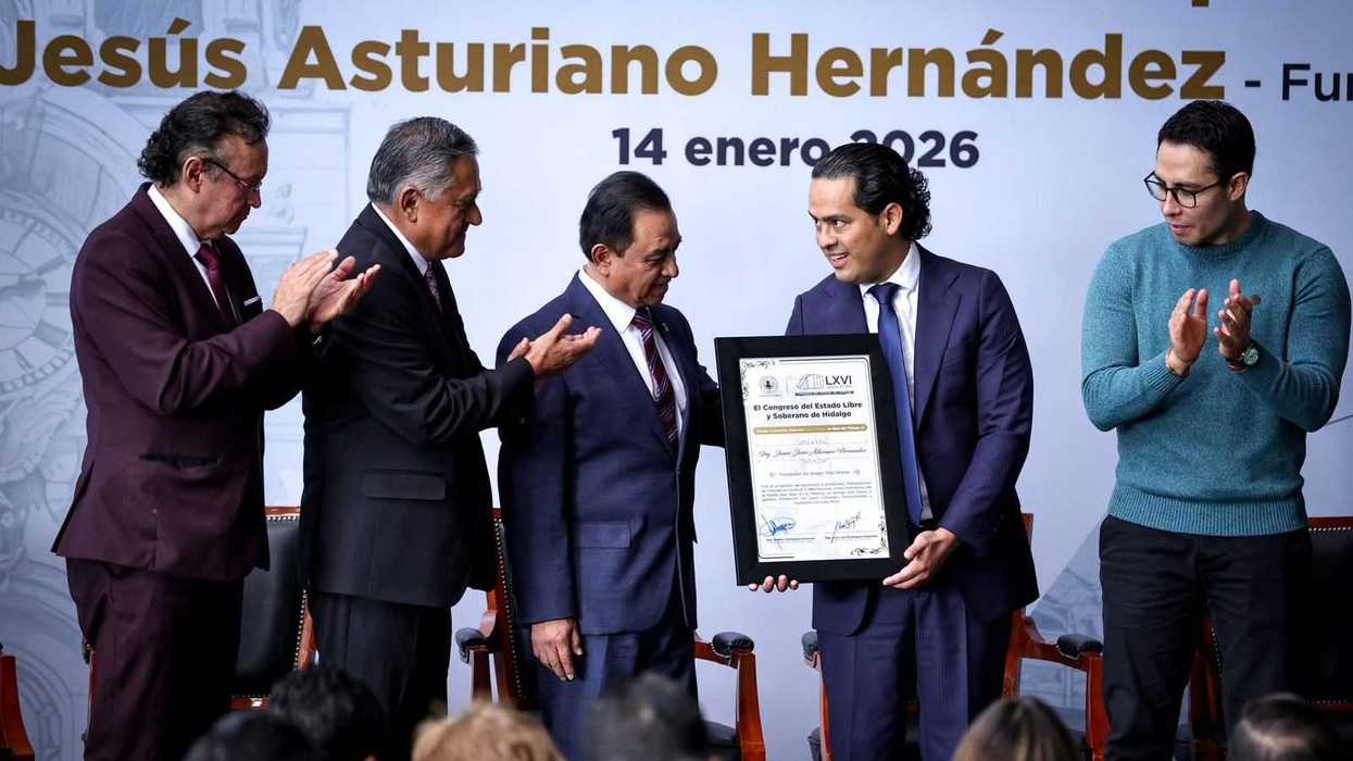 Award ceremony with five men, one holding a framed certificate, others clapping.