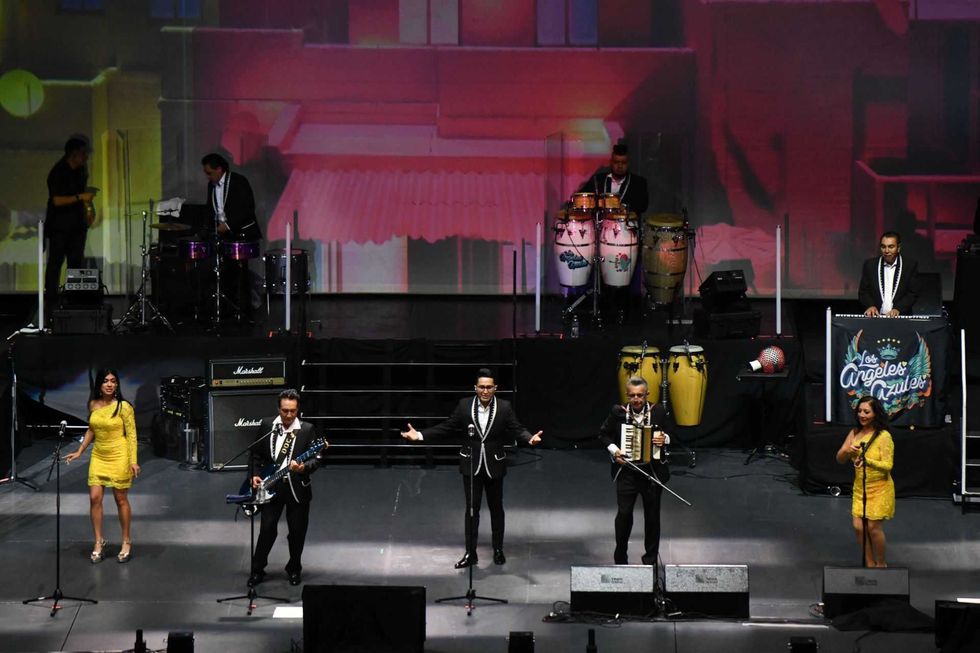 Band performing on stage with colorful lights and percussion instruments.