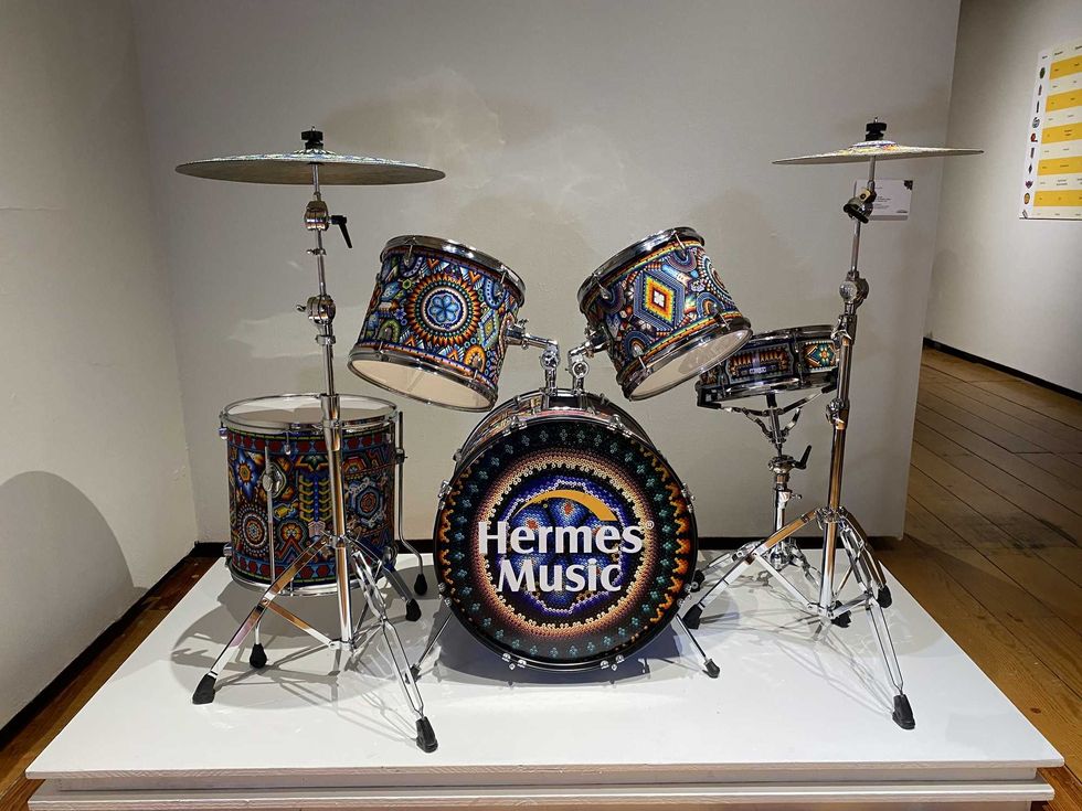 Beaded drum set with intricate patterns, displayed on a white platform.