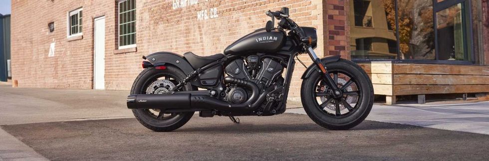 Black motorcycle parked by a brick building.