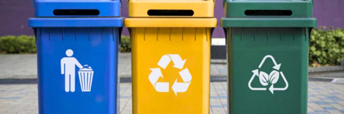 Blue, yellow, green recycling bins on a pavement for waste sorting.