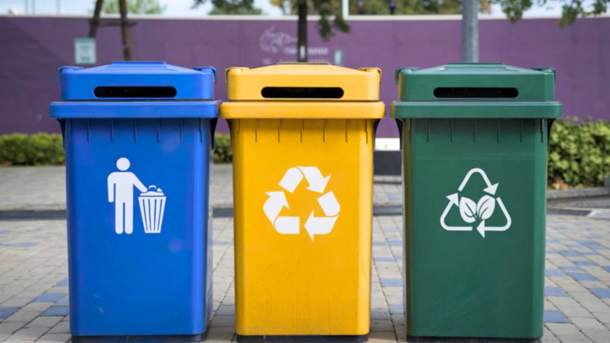 Blue, yellow, green recycling bins on a pavement for waste sorting.