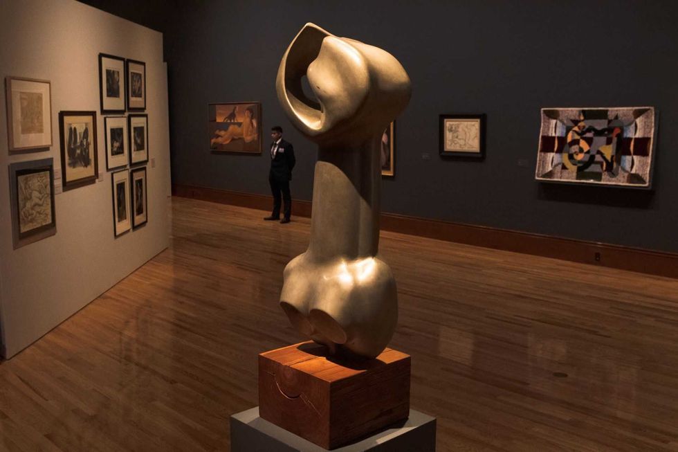 Bronze abstract sculpture in an art gallery with paintings on walls.