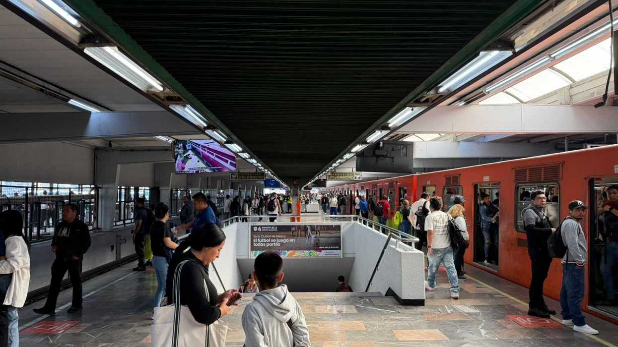 Busy subway platform with passengers boarding an orange train.