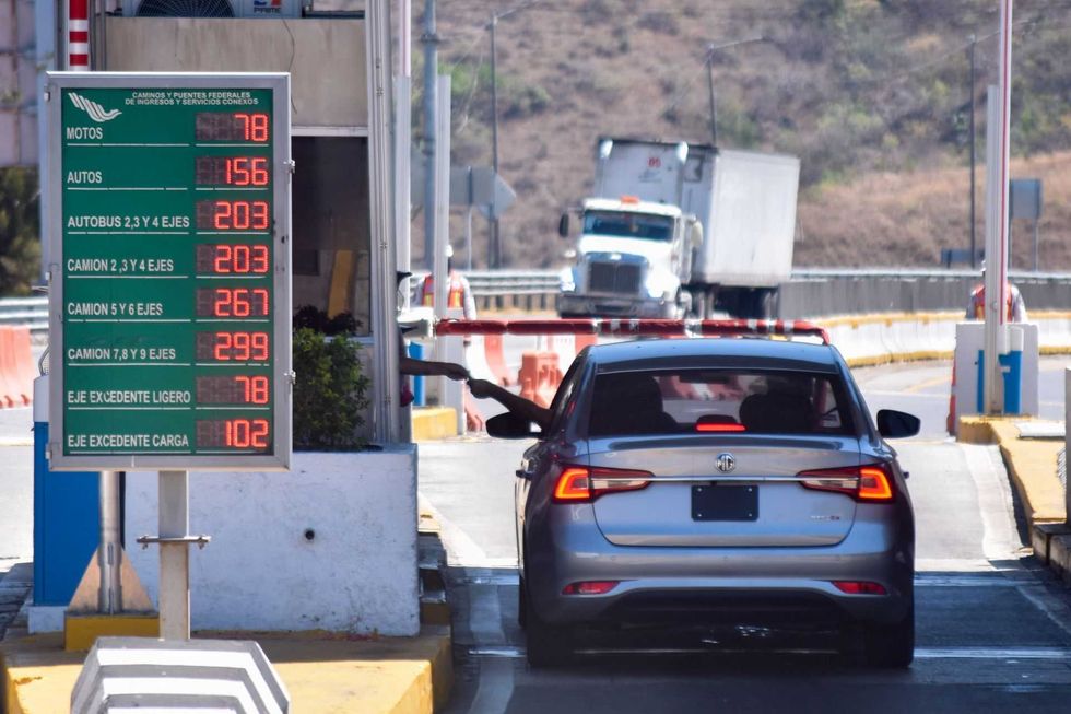 Car at a toll booth with a price sign for various vehicle types.