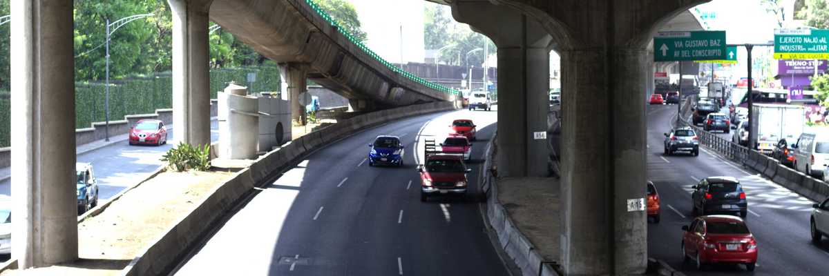 Cars driving on a multi-lane highway under an overpass.