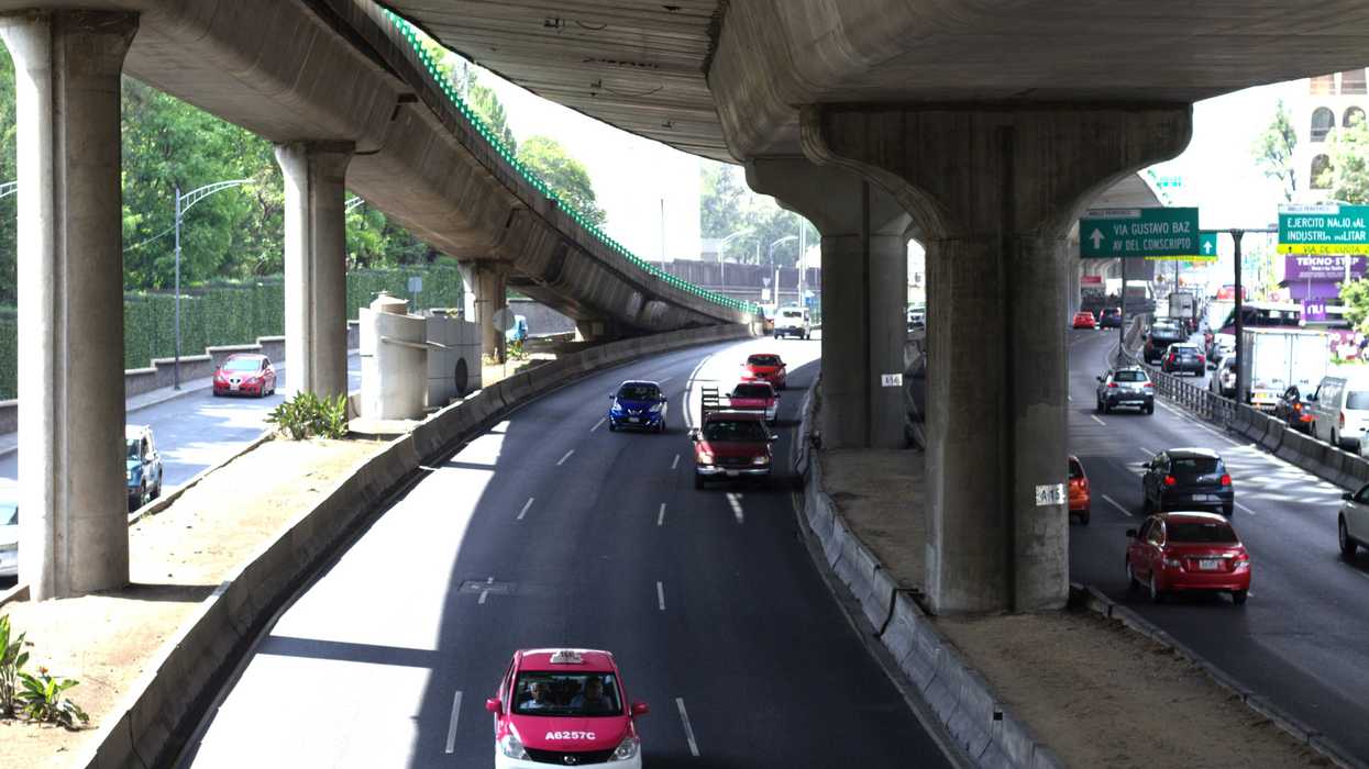 Cars driving on a multi-lane highway under an overpass.