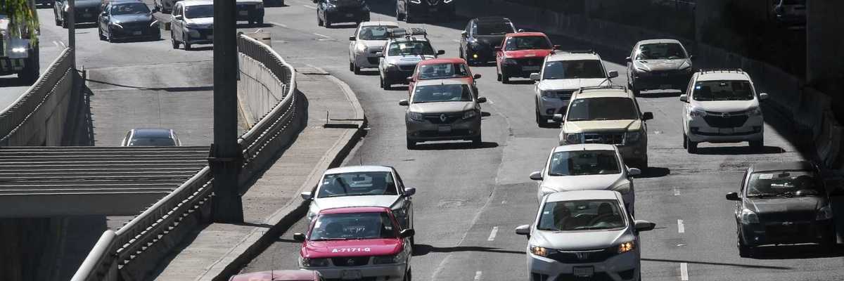 Cars on a busy multi-lane highway under an overpass during the day.