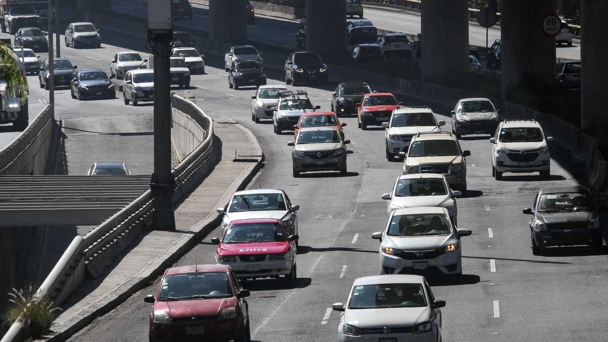 Cars on a busy multi-lane highway under an overpass during the day.