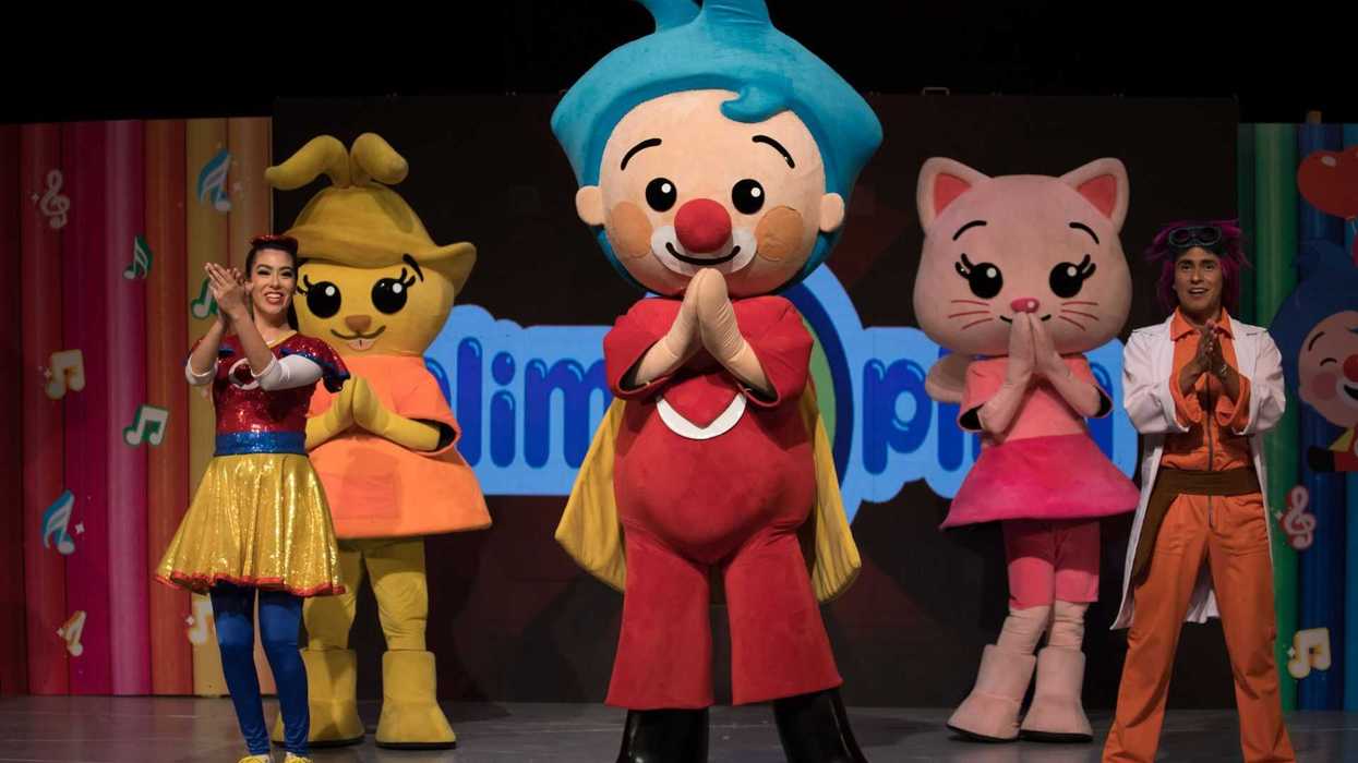 Characters in colorful costumes performing on stage, with a vibrant background.