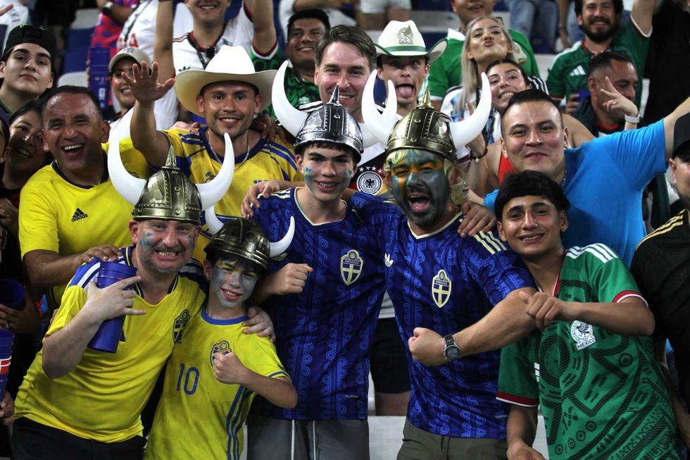 Cheerful soccer fans wearing colorful jerseys and Viking helmets at a stadium.