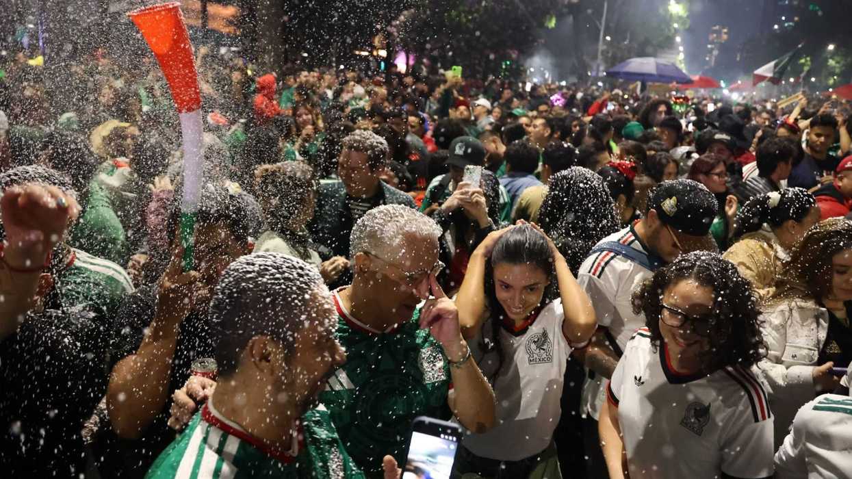 Cheering crowd celebrates in festive attire, confetti raining down.