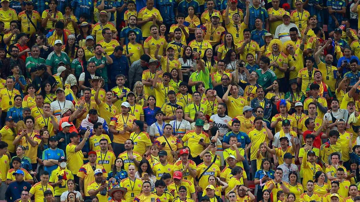 Cheering crowd in yellow jerseys at a sports event.