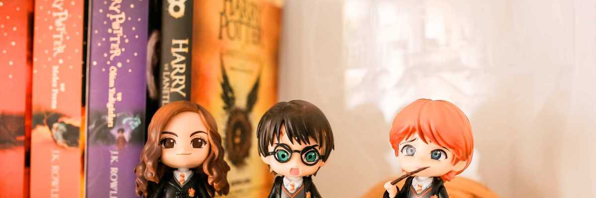 Chibi figures of wizards in front of Harry Potter books on a shelf.