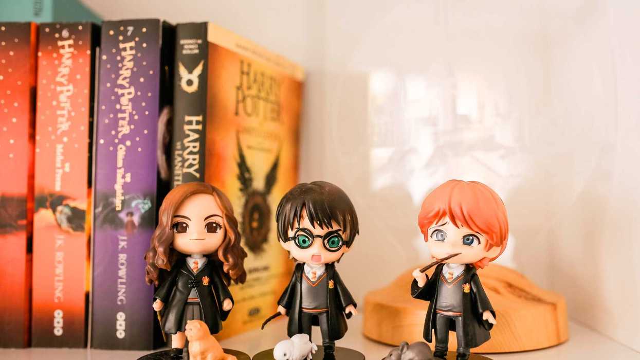Chibi figures of wizards in front of Harry Potter books on a shelf.