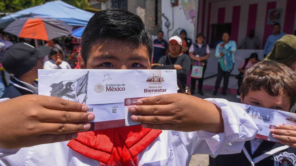 Child holding a government welfare envelope in a crowded outdoor setting.