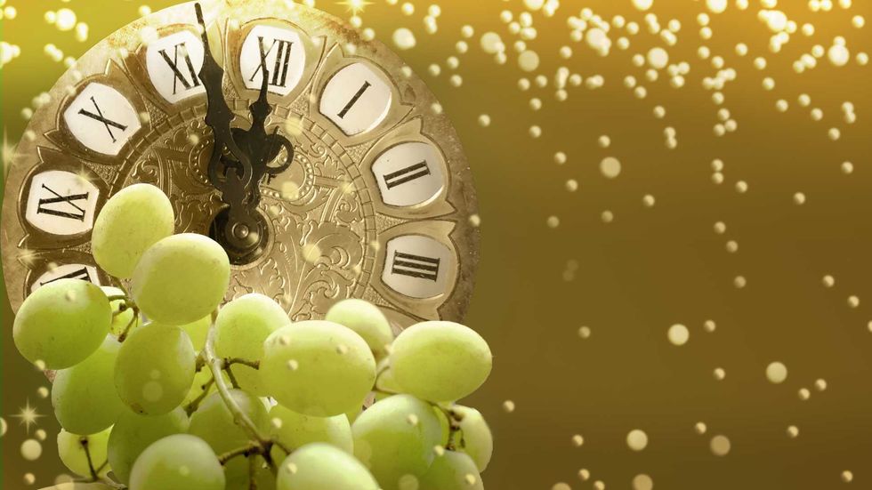 Clock with Roman numerals, green grapes, golden light, and sparkling bokeh.