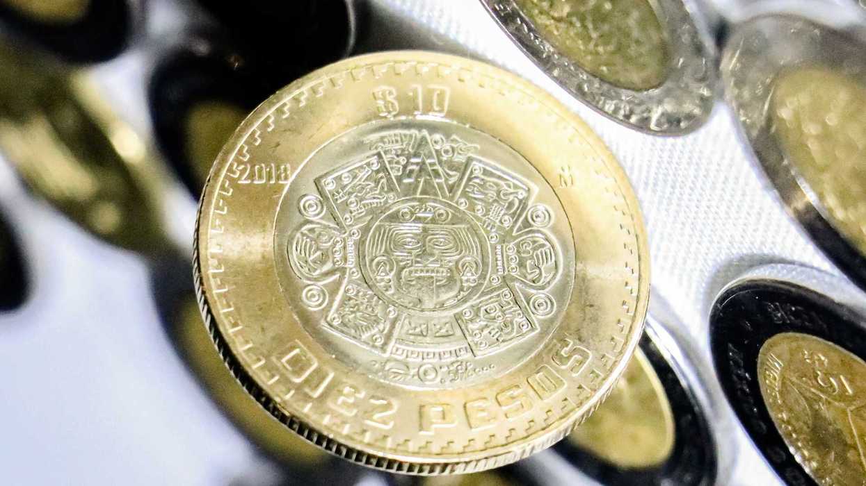 Close-up of a 10 pesos coin with intricate Aztec calendar design.