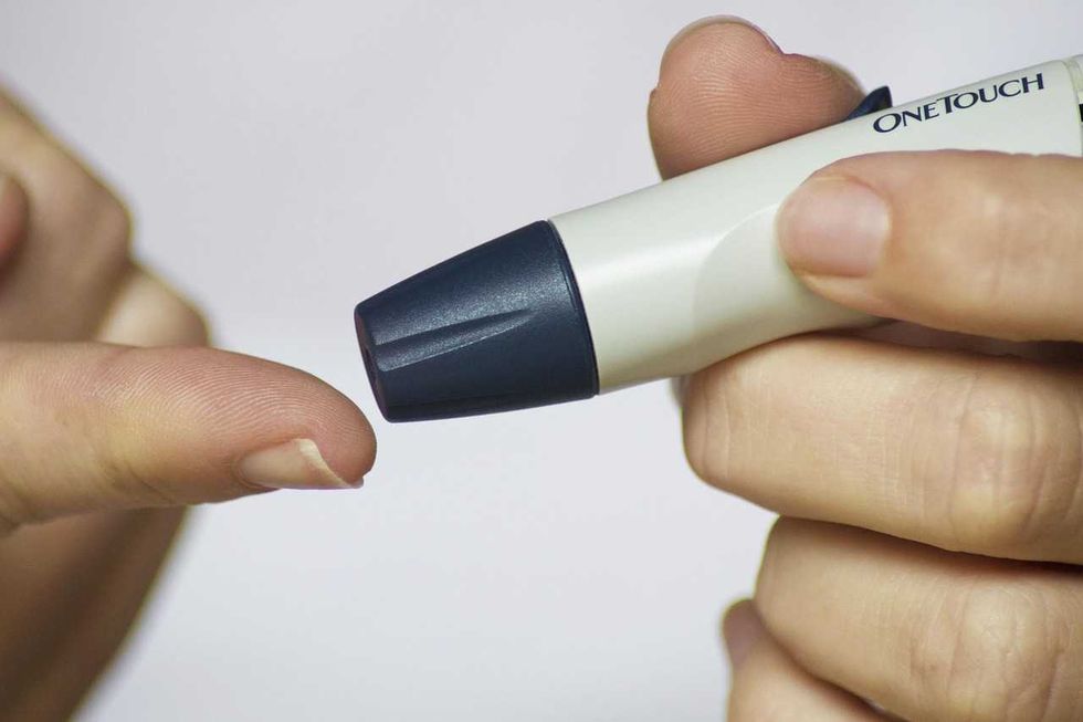 Close-up of a person using a glucose meter on their fingertip.