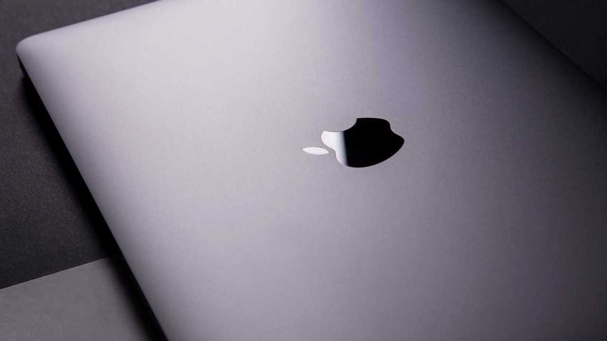 Closed silver laptop with reflective Apple logo on the lid.