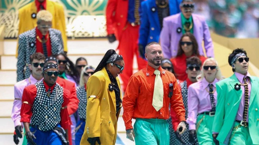 Colorful dancers in vibrant suits walking down steps during an outdoor performance.