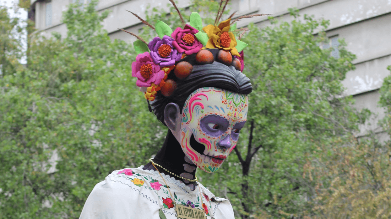 Colorful Día de los Muertos statue with floral headdress and intricate face paint.