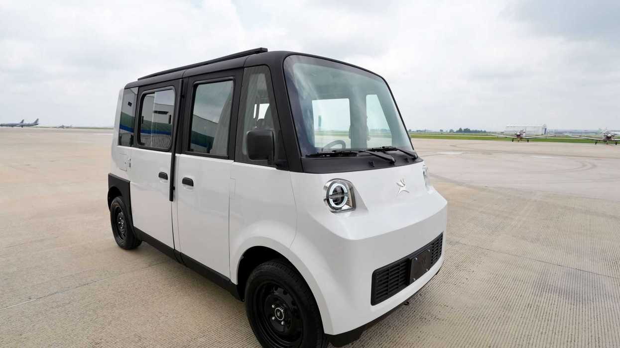 Compact white and black minivan parked on an empty airport tarmac.