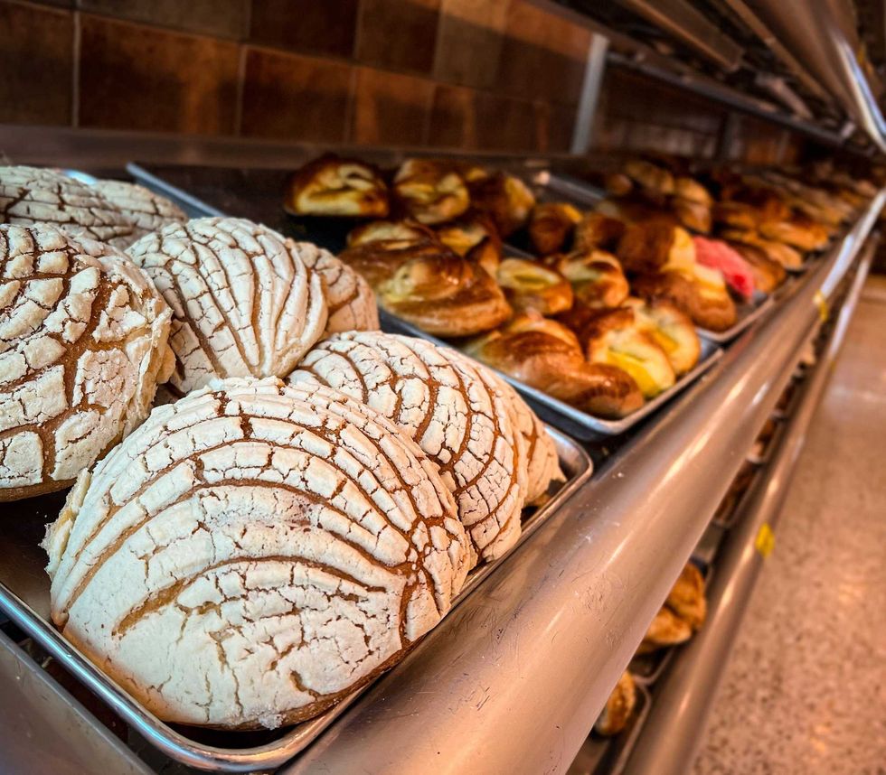 Concha tradicional acompa\u00f1ada de otras piezas de pan dulce mexicano en una canasta.