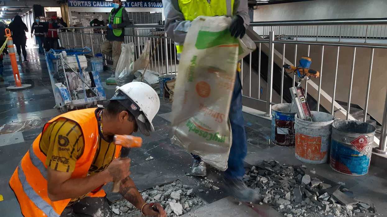 Construction workers repairing floor in a public area, using tools and materials.