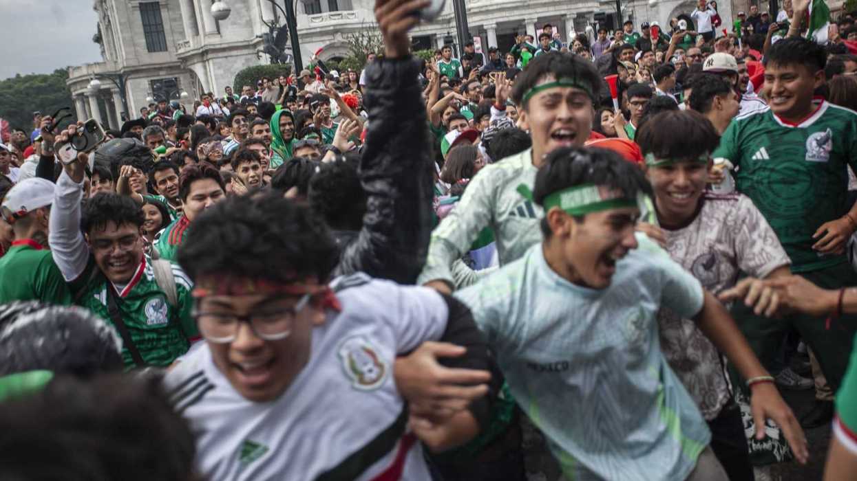 Crowd celebrating enthusiastically, many wearing green football jerseys and headbands, outdoors.