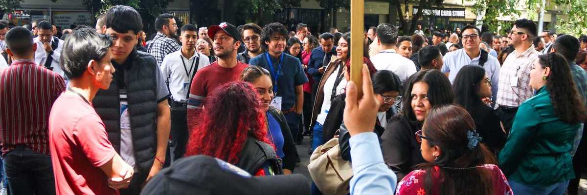 Crowd gathered outdoors holding "Punto de Reunión" sign.