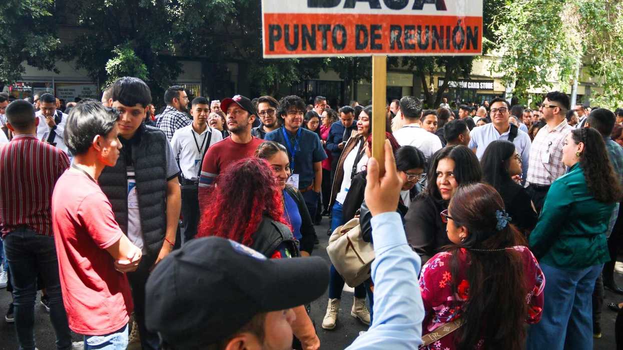Crowd gathered outdoors holding "Punto de Reunión" sign.