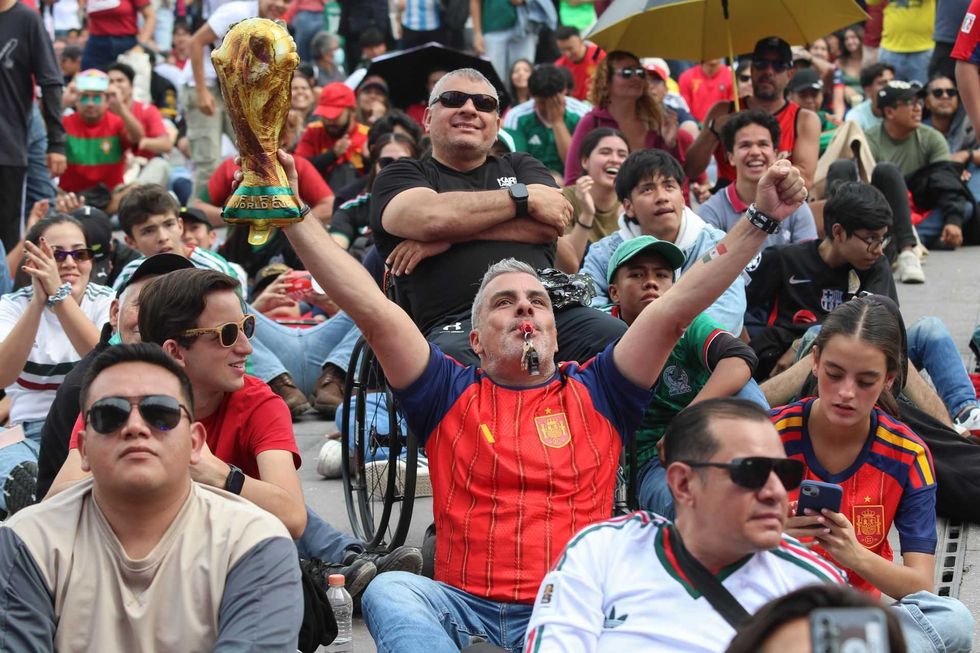 Crowd of passionate fans celebrating, man raising a trophy.